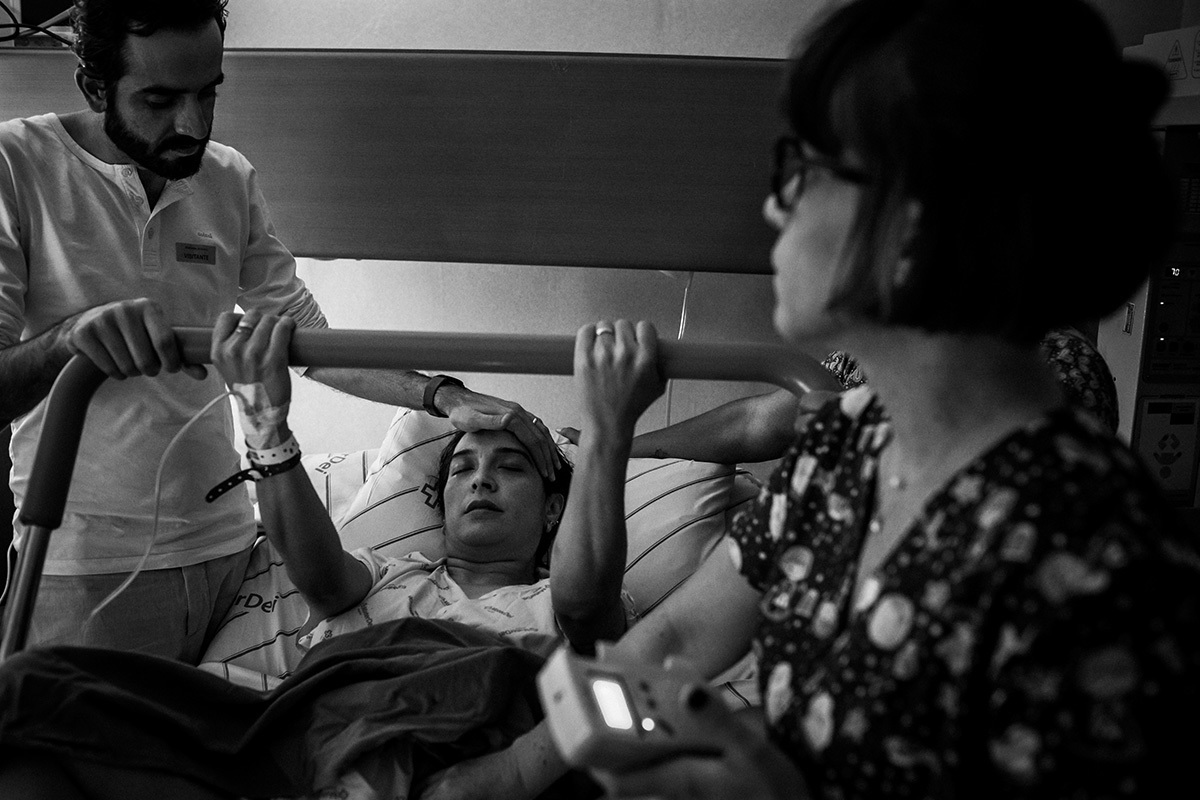 parturiente apoiada por seu marido e enfermeira obstétrica já quase na hora de seu bebê nascer, por adrianacostafotos