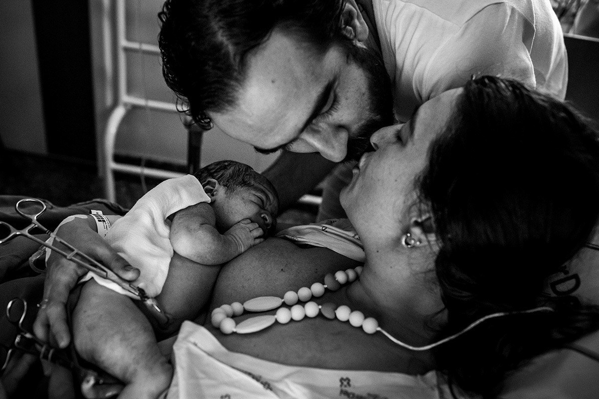 casal se beijam emocionados após cortar o cordão umbilical do filho, por Adriana Costa
