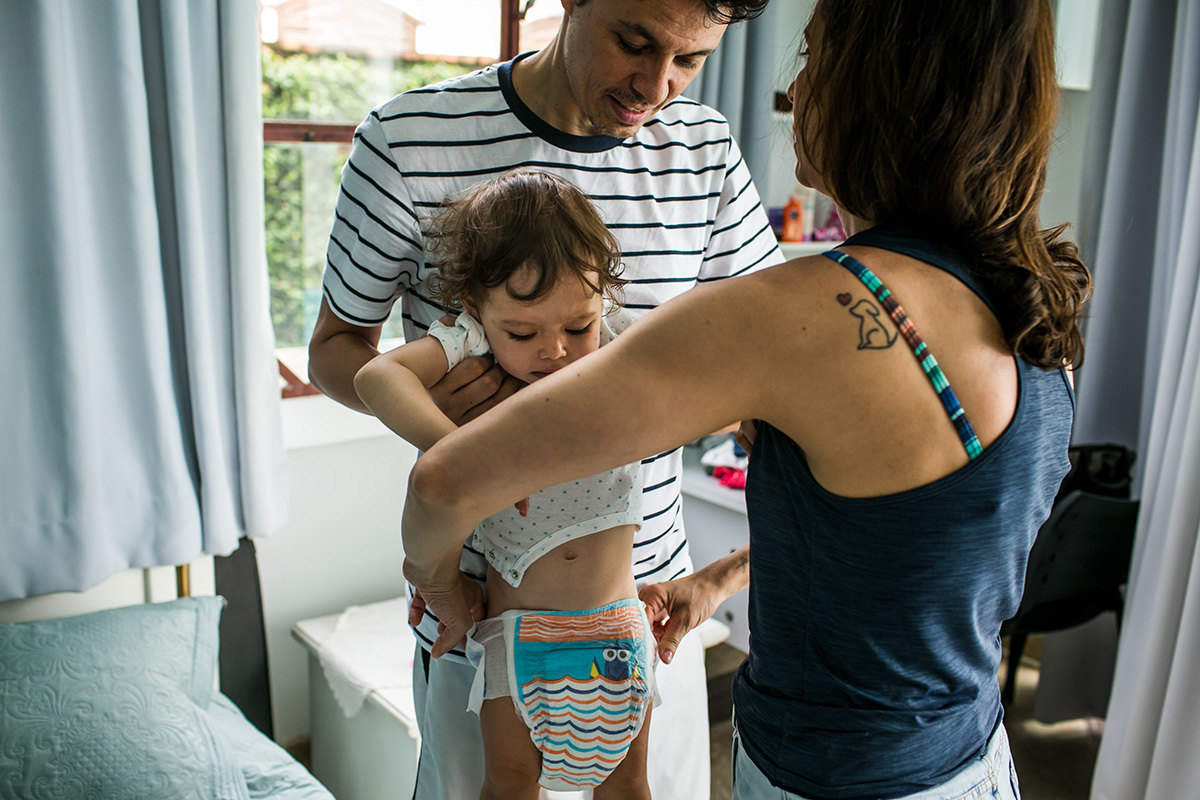pais trocando a fralda da filha