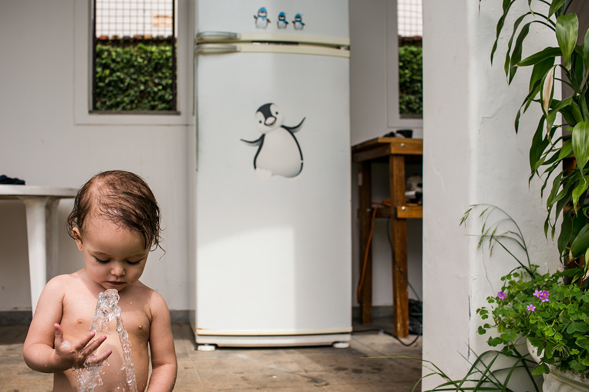 menina de 1 ano brinca com a água da mangueira