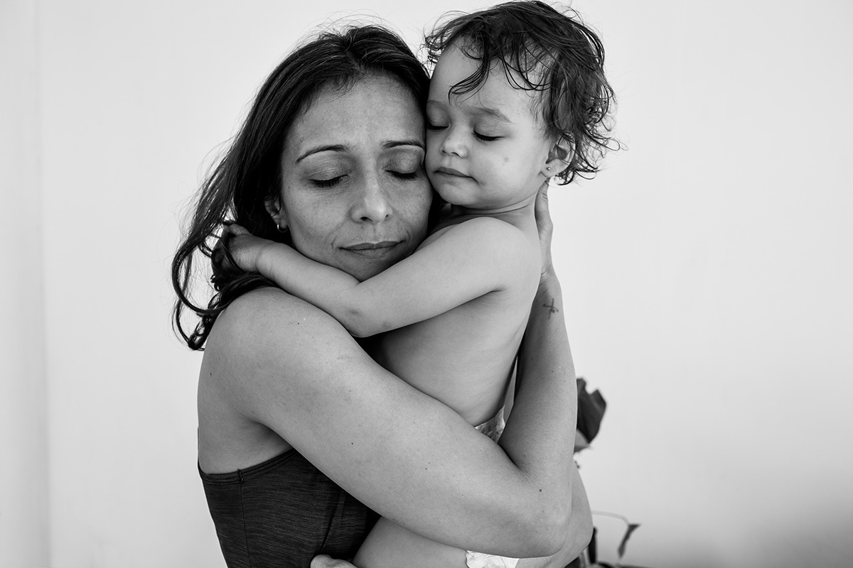mãe abraça a filha com carinho em foto de Adriana Costa