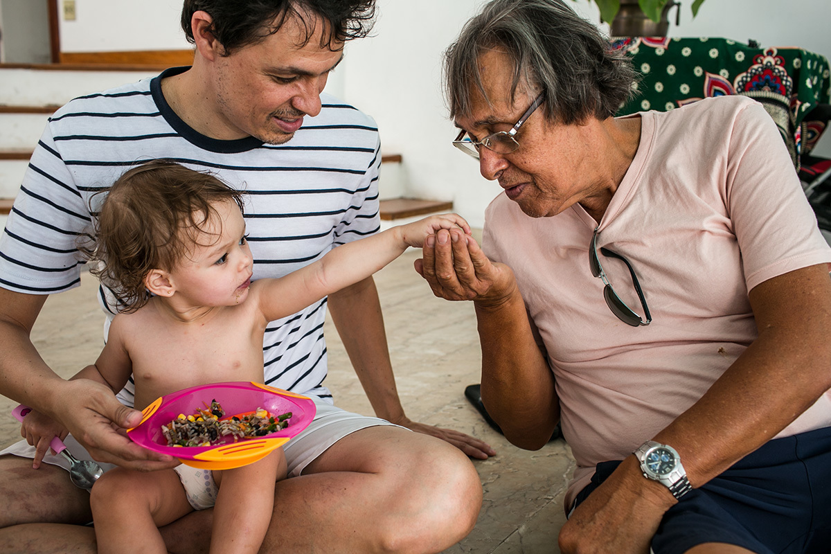 menina dá um pouco de sua comida para o avô