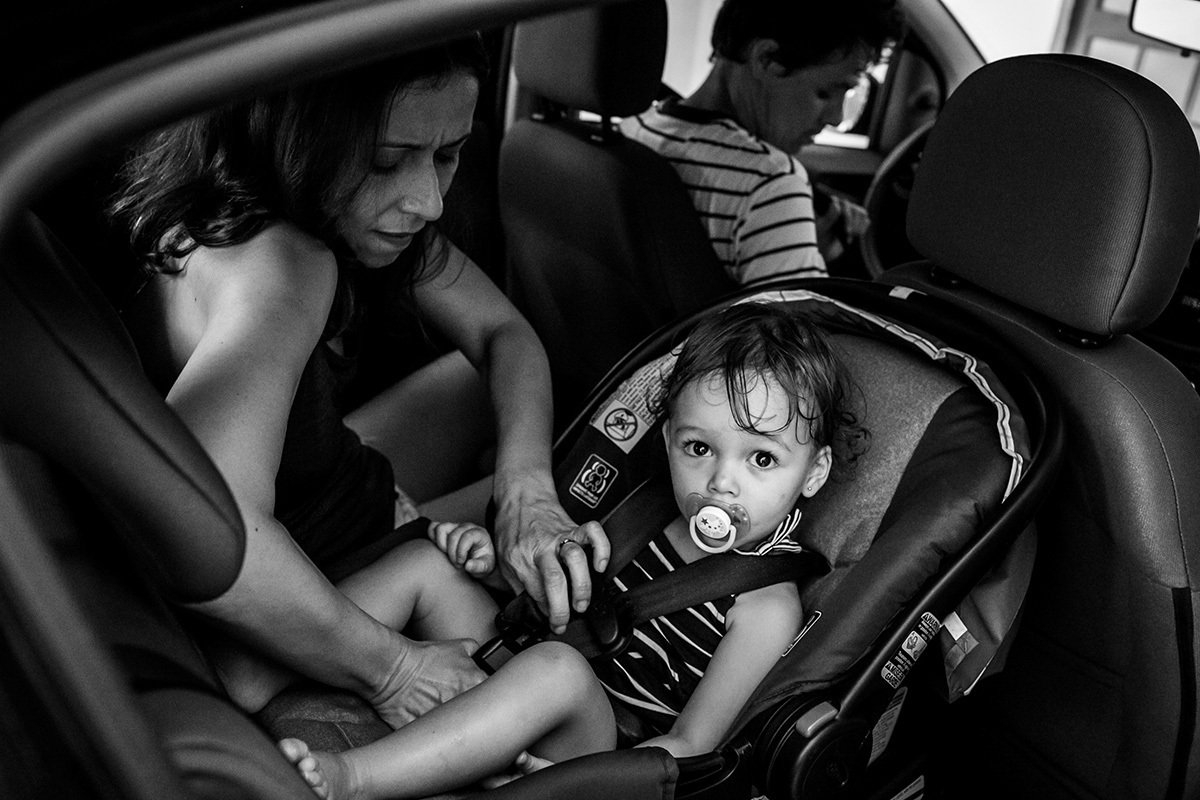 mãe coloca filha na cadeirinha do carro