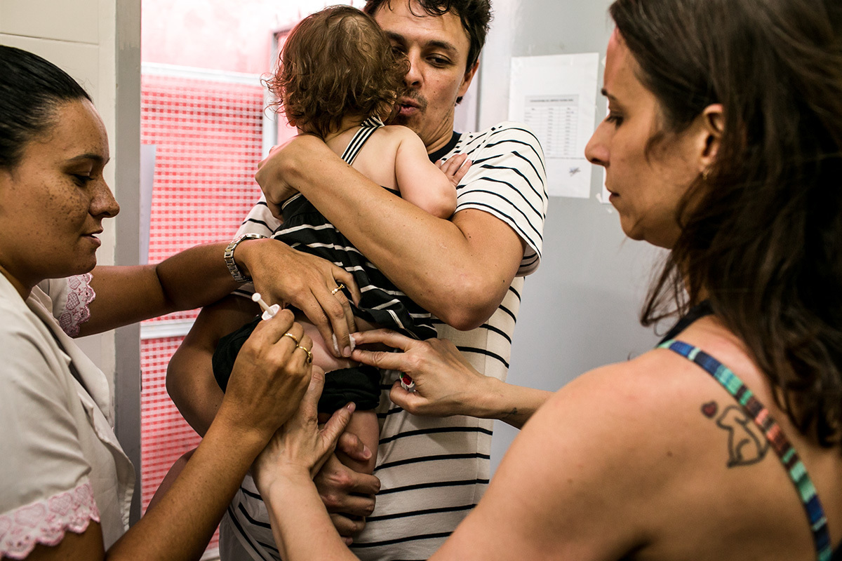 pais levam sua bebê para vacinar