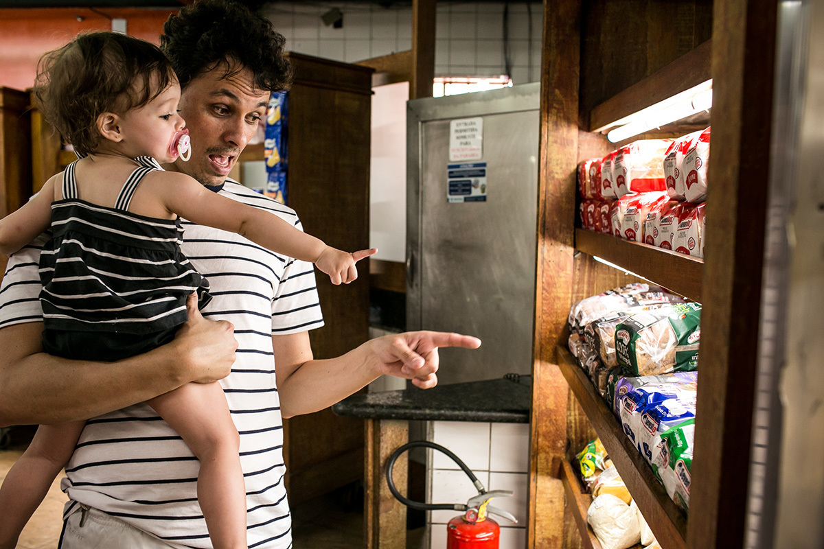 pai brinca com a filha na padaria do bairro