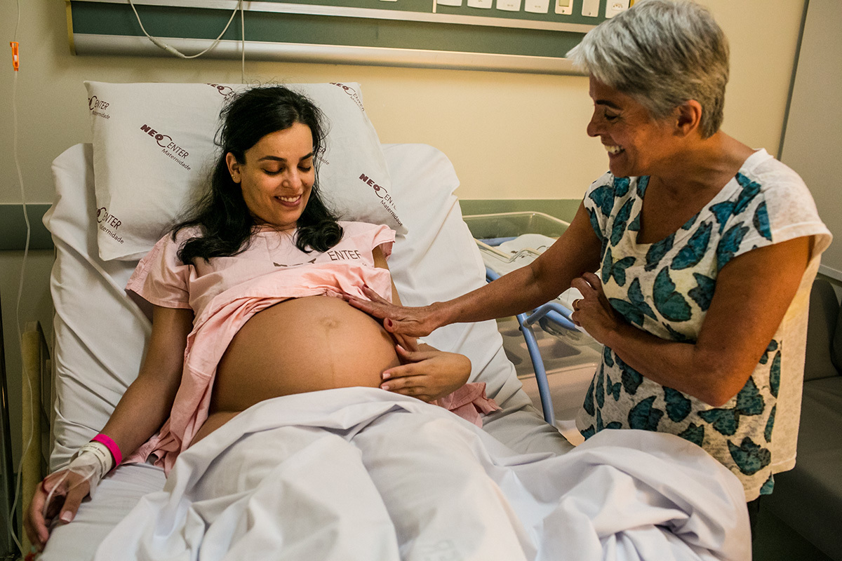 mãe faz carinho na barriga da filha que está em trabalho de parto