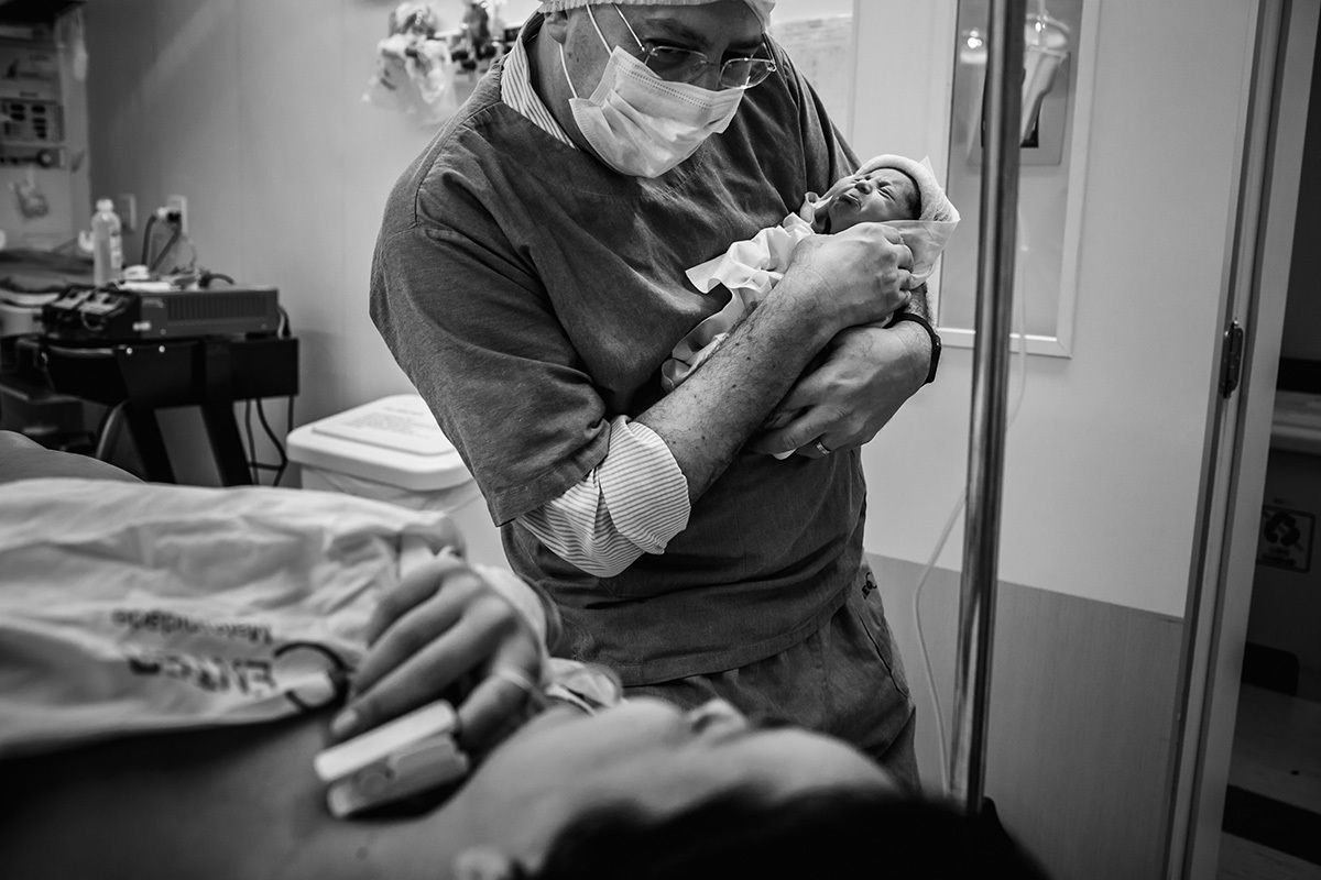 pai mostra sua bebê fazendo caretinha para a mãe ainda no bloco cirúrgico, após cesárea