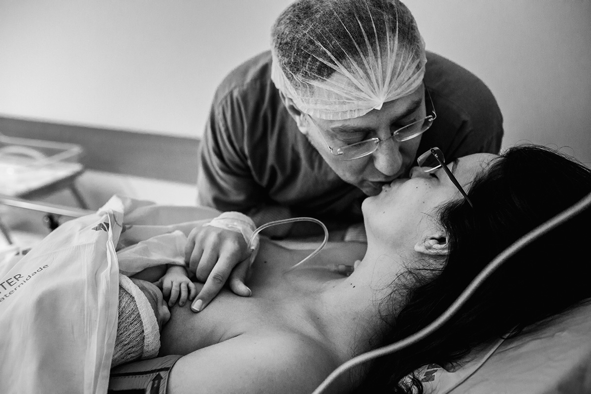 casal emocionados com sua filha se beijam na sala de recuperação da maternidade Neocenter pós cesárea, por Adriana Costa