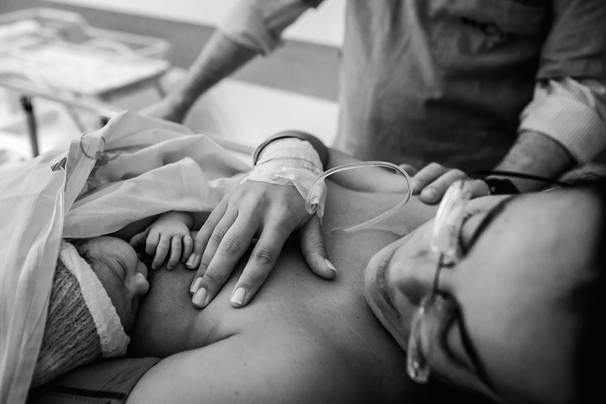 mãe amamentando sua filha na sala de recuperação pós cesárea da maternidade Neocenter em companhia do seu marido