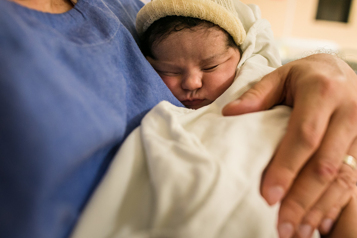 bebê dorme no colo do pai após sua primeira amamentação pós nascimento