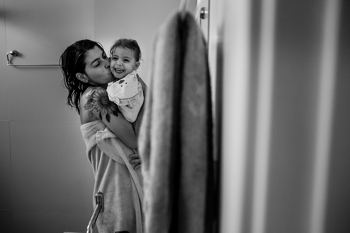 foto de Adriana Costa da mãe beijando sua filha ao sair do banho ainda enroladas na toalha