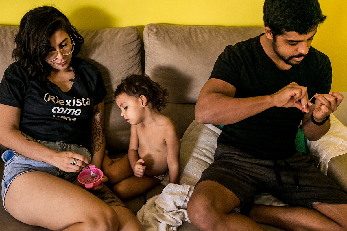 mãe dá sorvete para filha enquanto pai corta a unha