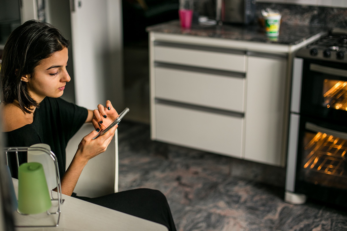 conversando com os amigos pela internet enquanto espera assar o bolo que prepara para o seu aniversário que caiu durante a quarentena pelo covid-19