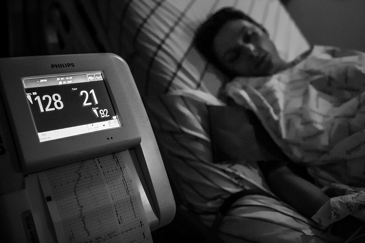 mulher sendo monitorada pós anestesia enquanto descansa em quarto escuro durante seu trabalho de parto, por adrianacostafotos