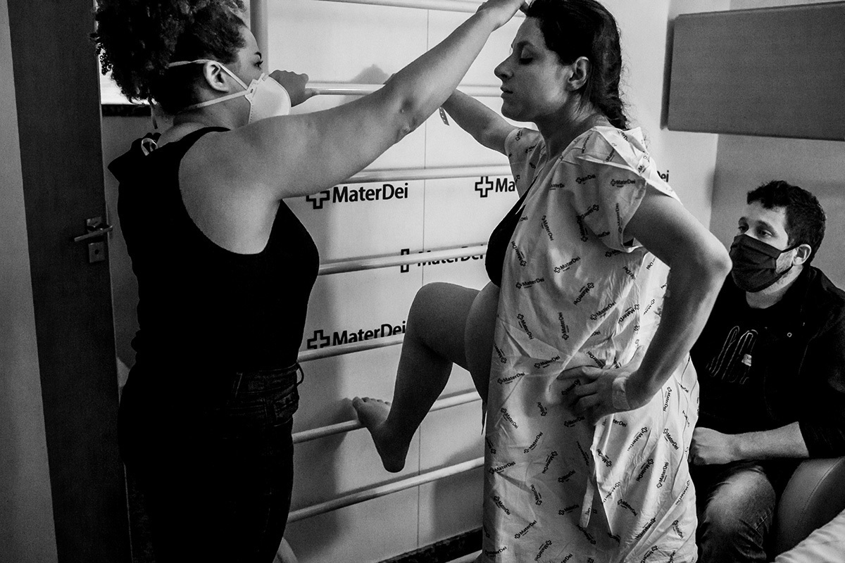 mulher na suíte de parto do Mater Dei fazendo exercícios com sua doula para ajudar no trabalho de parto