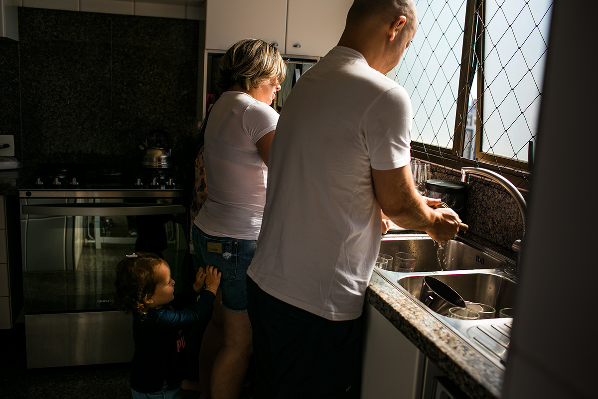 mãe gravida arrumando a cozinha com o marido e sua outra filha