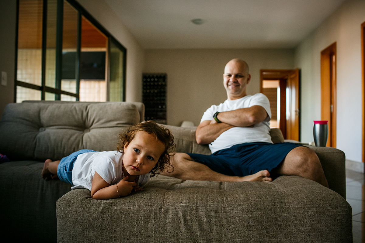 pai rindo de como a filha está assistindo televisão