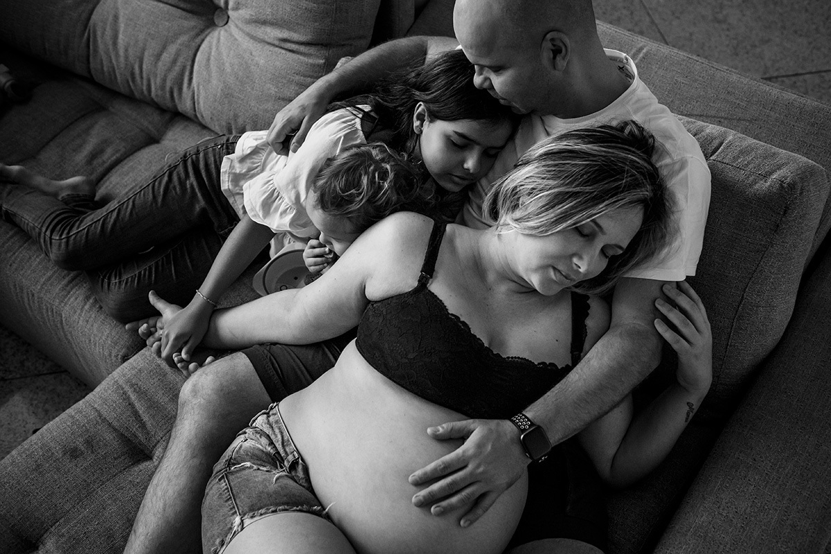 família abraçada à mãe que está grávida da terceira filha