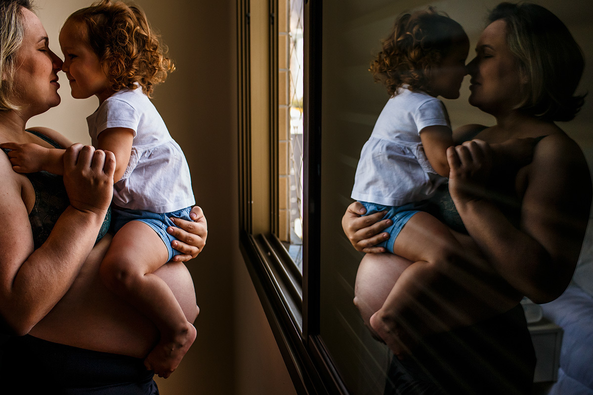 mãe gravida brinca com sua filha no colo