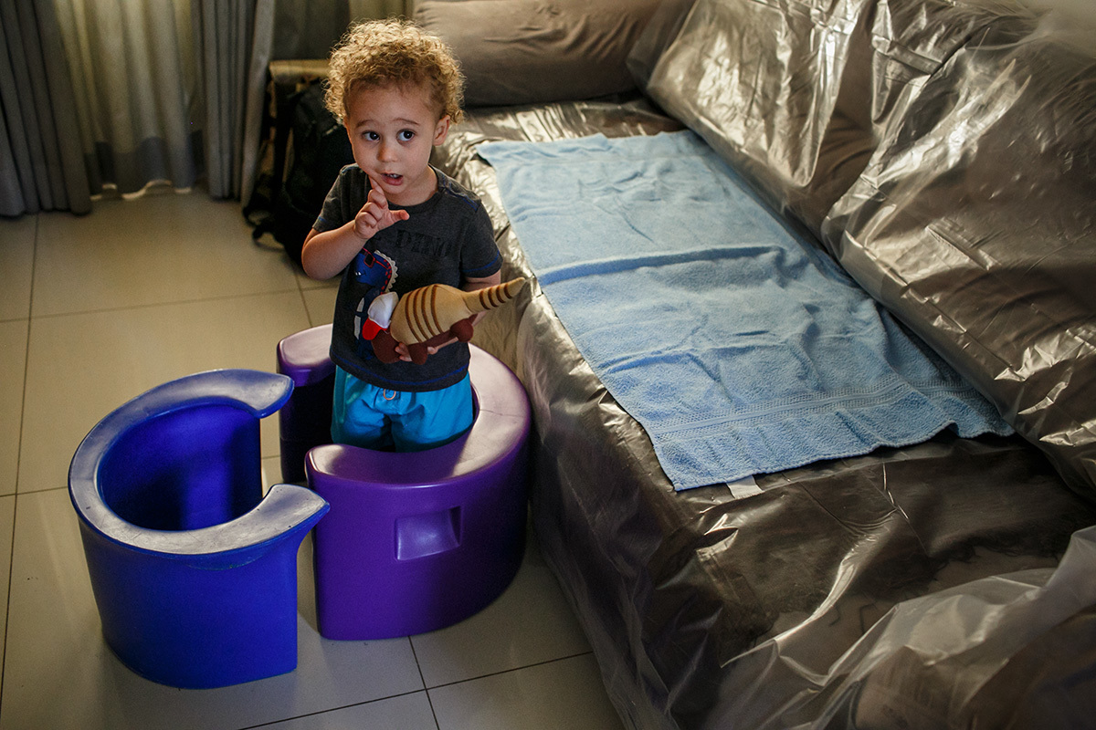 Foto de Adriana Costa da criança brincando entre as banquetas de parto que estão na sua casa para o parto domiciliar do seu irmão