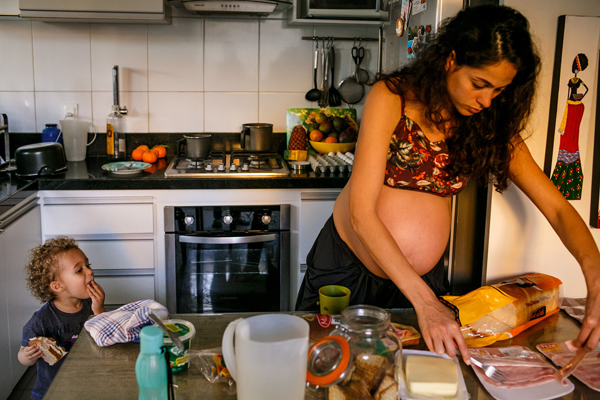mãe em trabalho de parto domiciliar prepara o lanche para seu primeiro filho