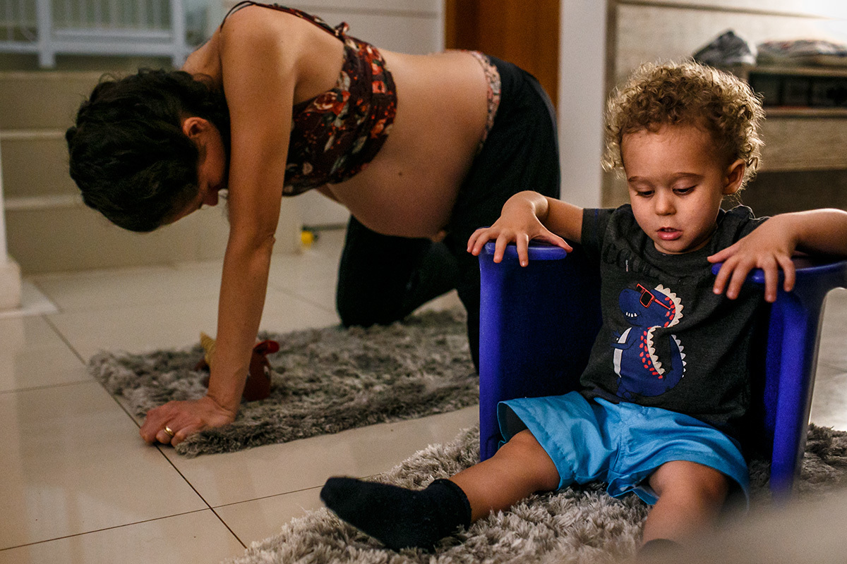 criança brinca com a banqueta de parto enquanto sua mãe tem contrações pelo parto do segundo filho
