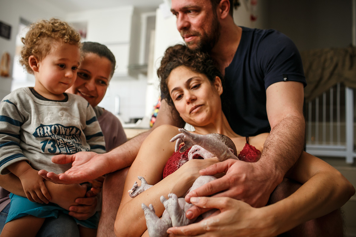 menino observa seu irmão que acabou de nascer durante um parto domiciliar