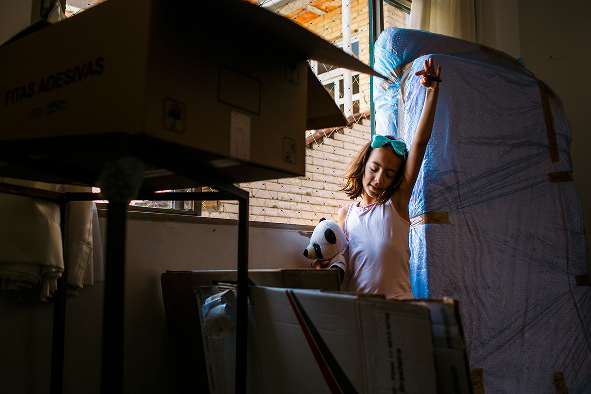 Foto de Adriana Costa da criança brincando em meios aos objetos embalados para a sua mudança