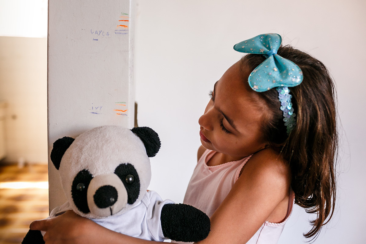 Adriana Costa fotografou menina colocando seu ursinho na marca da parede de seu crescimento no dia de se mudar da casa onde nasceu