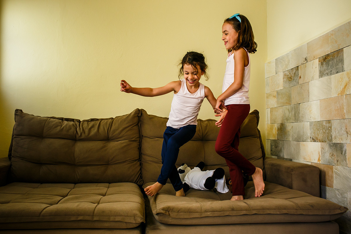 crianças pulando no sofá no dia da mudança de casa em foto de Adriana Costa