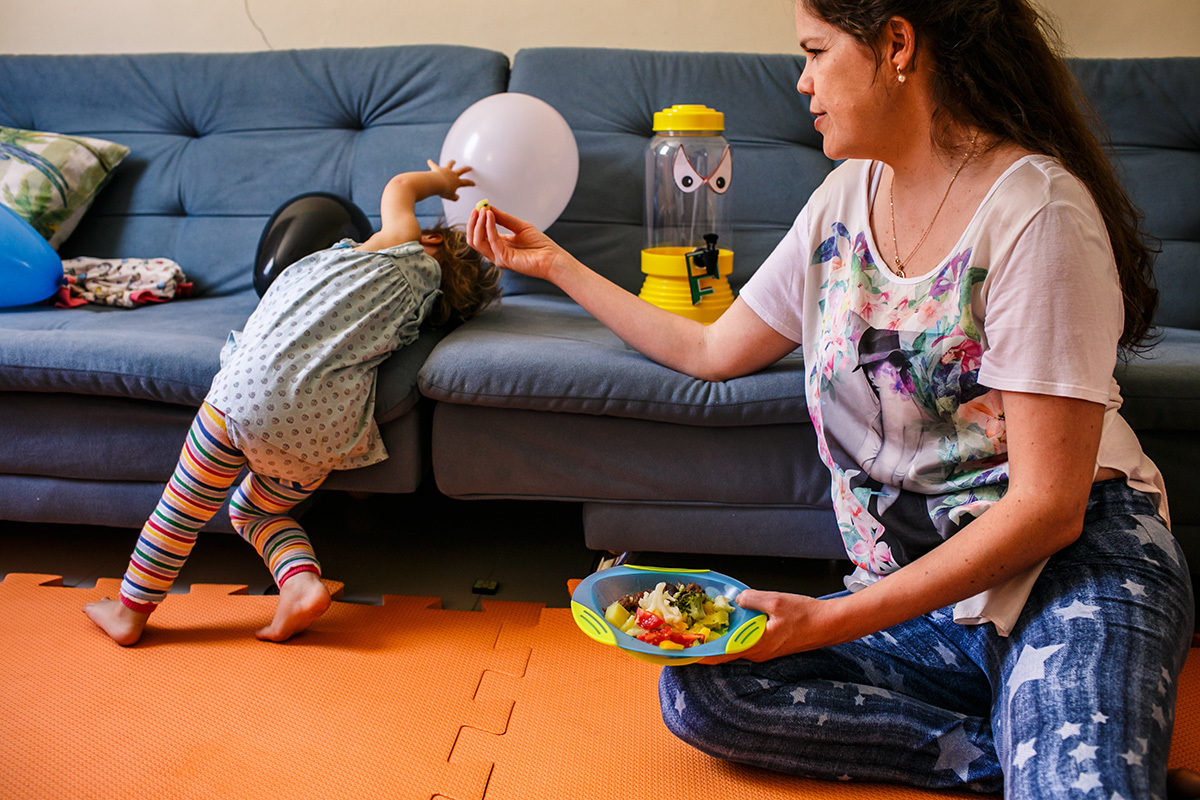 criança fugindo da comida que a mãe oferece
