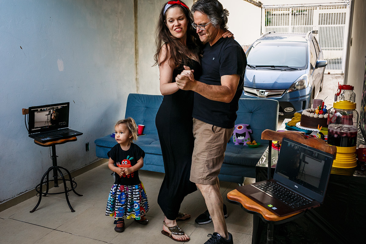 foto de Adriana Costa dos pais dançando durante a festa de aniversário de sua filha em casa com a família participando on-line devido a pandemia