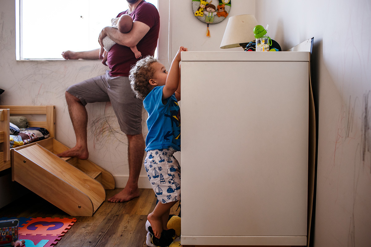 pai com seu bebé recém-nascido observa filho mais velho fazer arte