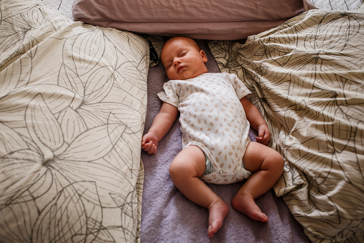 bebê recém-nascido dormindo na cama dos pais