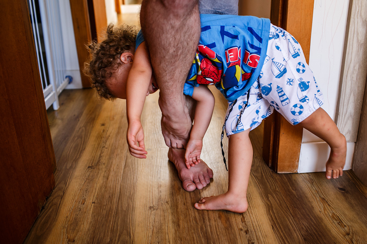 pai impedindo com os pés a passagem do filho em foto de Adriana Costa
