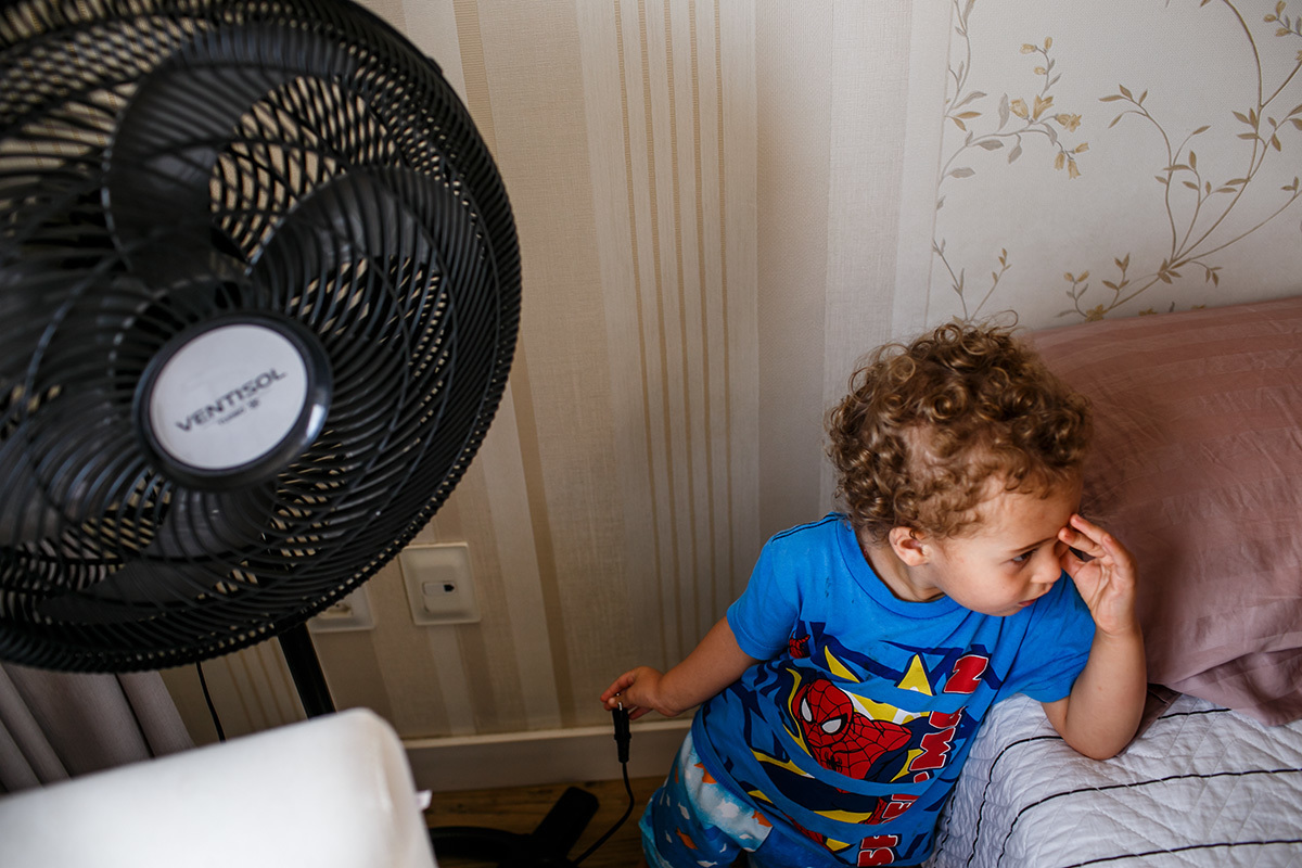 menino segurando a tomada do ventilador