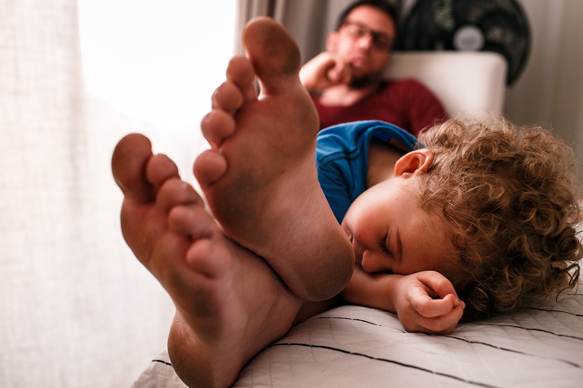 menino deita sobre os pés do pai