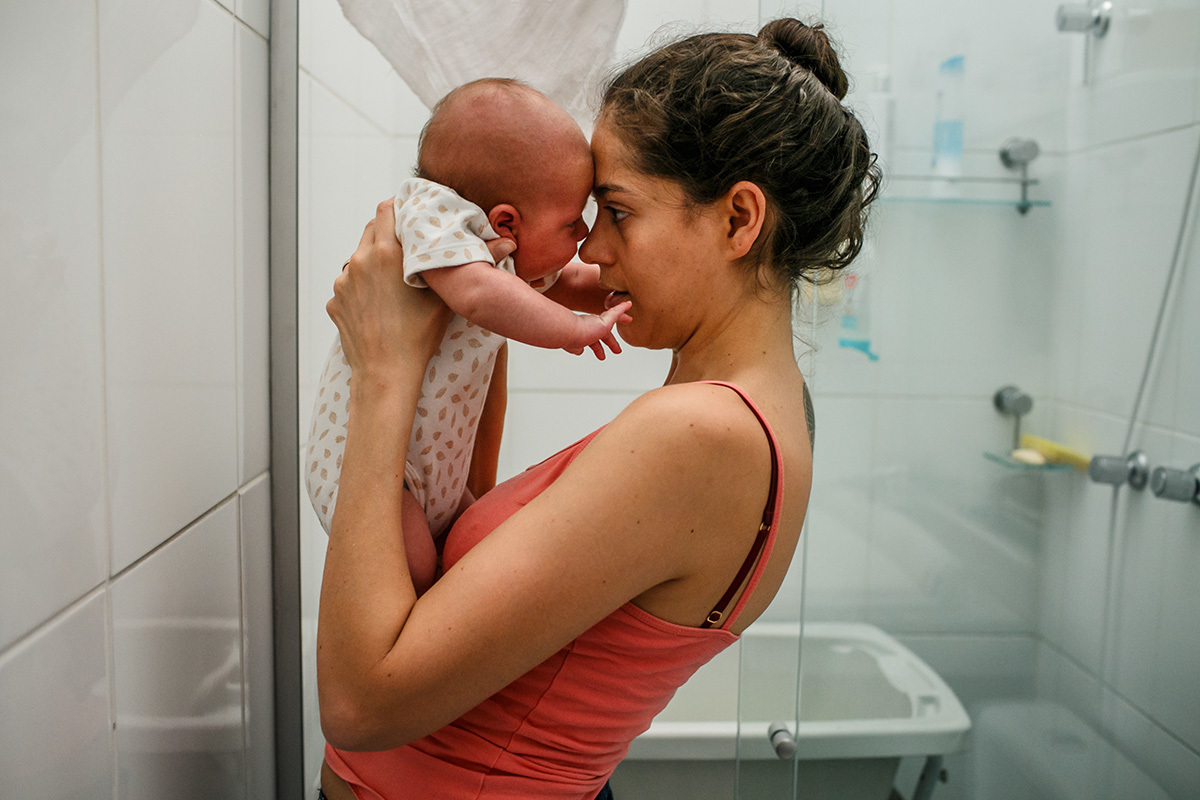 mãe e seu bebê recém-nascido em momento de carinho antes de iniciar o banho em foto de Adriana Costa