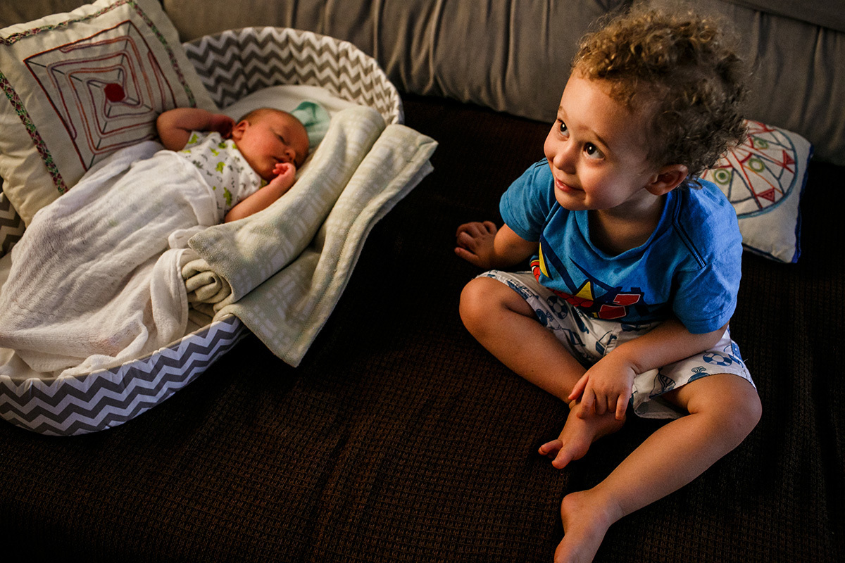 menino sorrindo ao lado de seu irmão recém-nascido