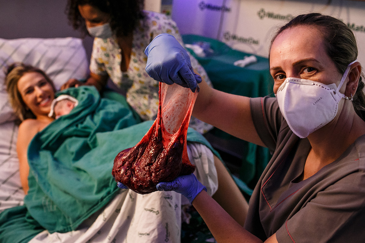 Enfermeira do Instituto Nascer mostra a placenta para a mulher
