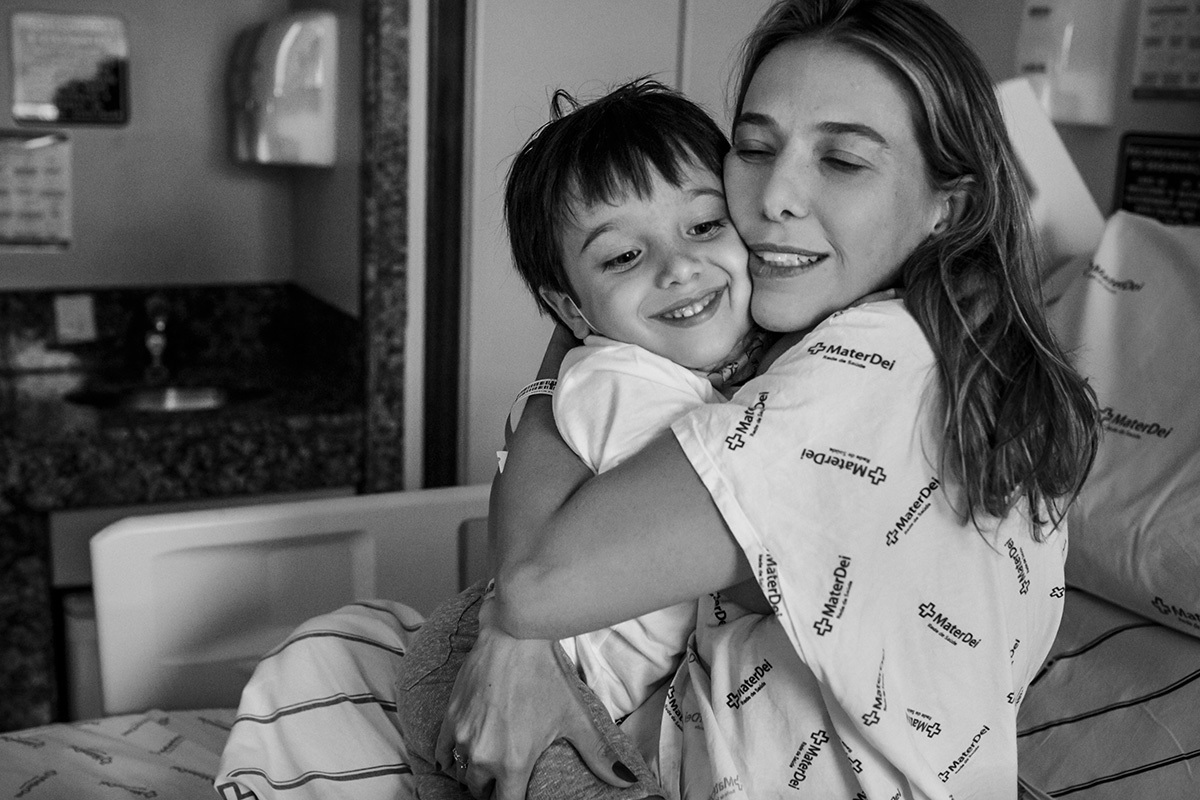 Mãe abraça emocionada seu filho mais velho após o parto