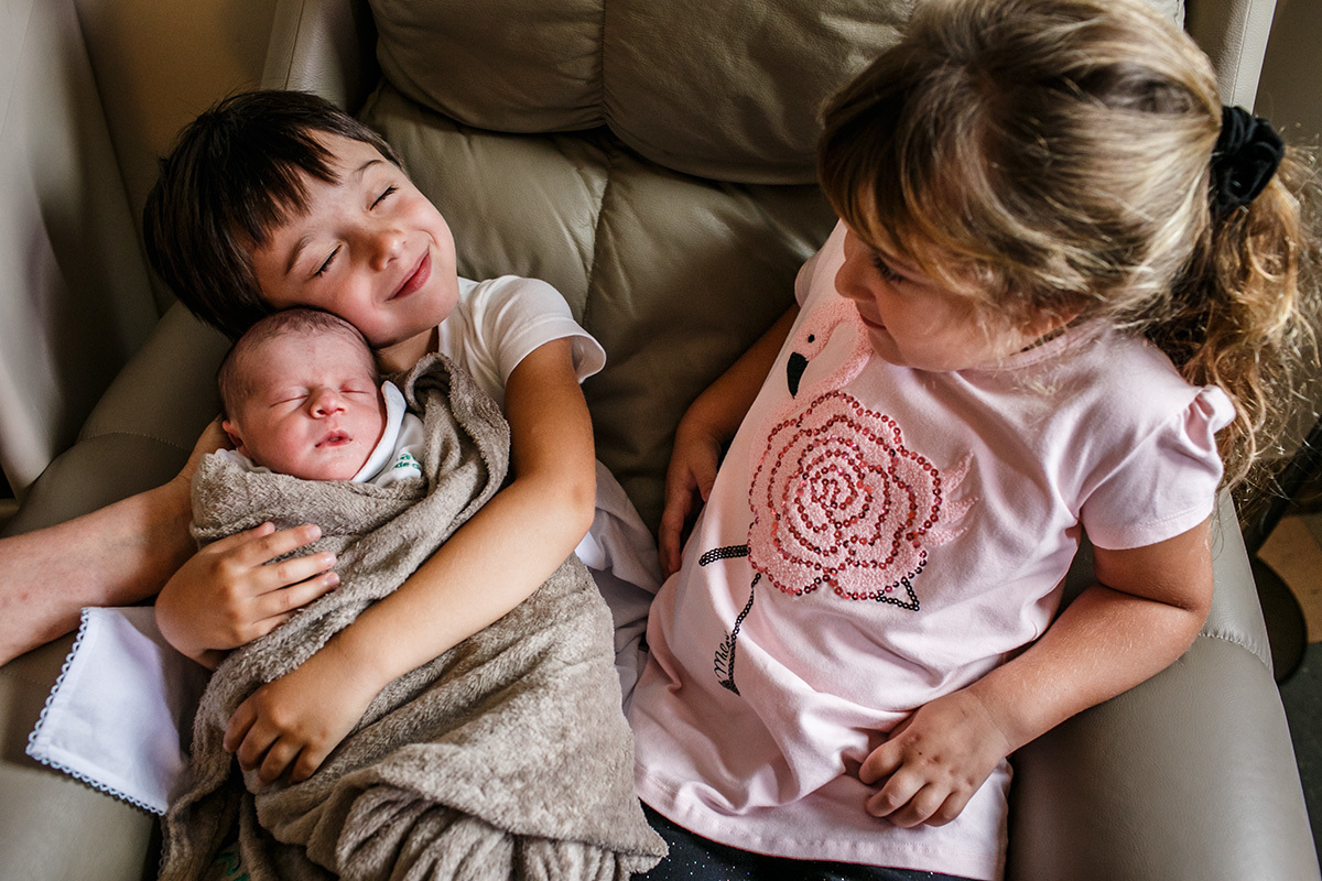 menino abraça com carinho seu irmão que acabou de nascer