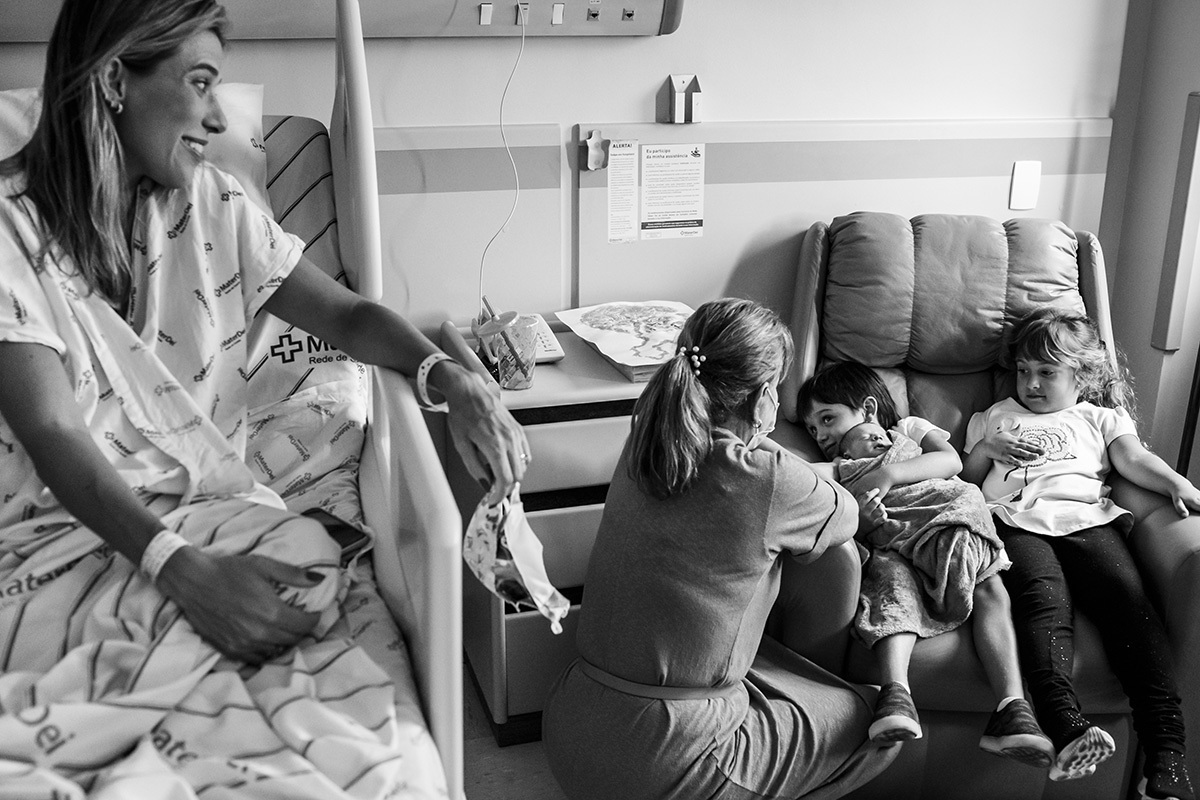 mãe observa o carinho do seu filho mais velho com seu bebê que acabou de nascer