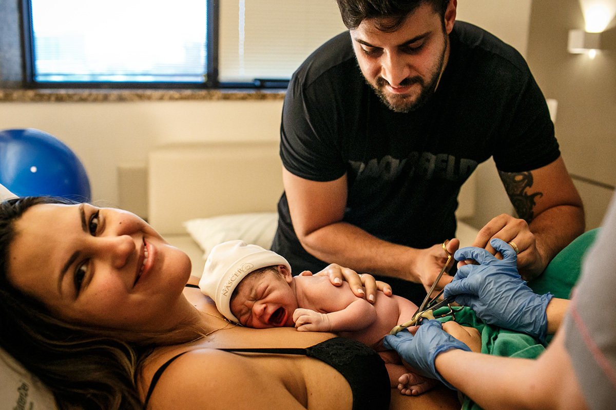 pai cortando o cordão umbilical após o nascimento da filha de parto natural