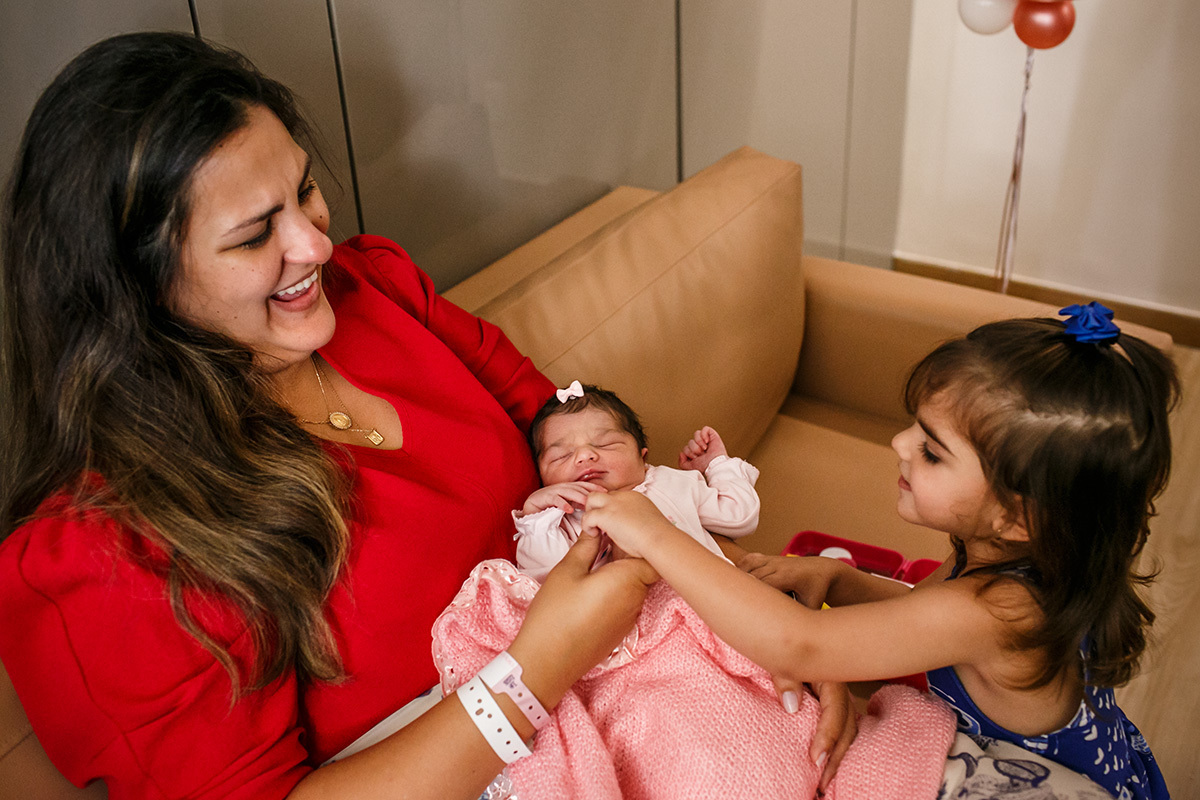 menina brinca de examinar a irmã que acabou de nascer na Maternidade Mater Dei