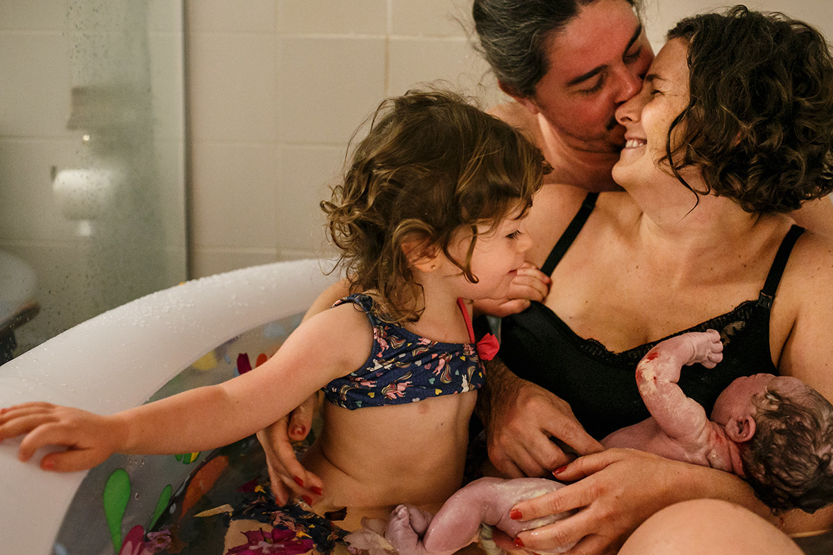 Foto de Adriana Costa do casal e sua filha mais velha recebendo o seu bebê que acabou de nascer em um parto domiciliar