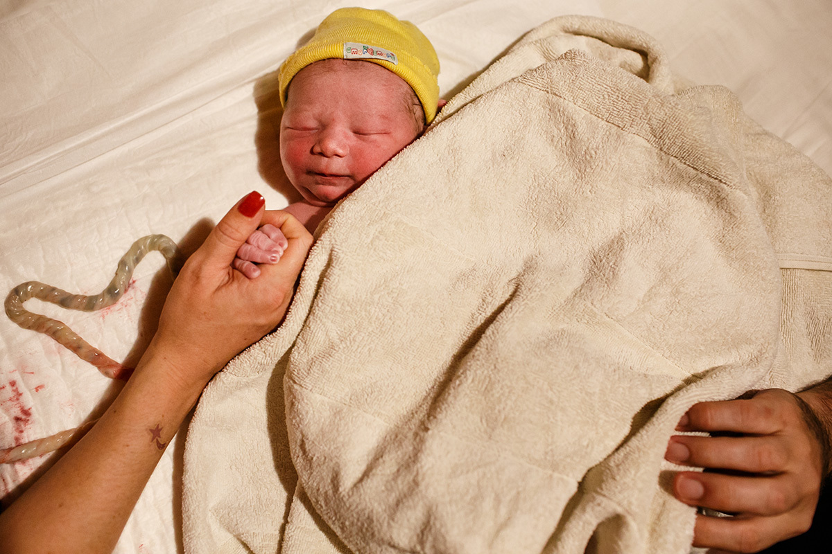 bebê ainda ligado a placenta fica tranquilo ao lado de seus pais