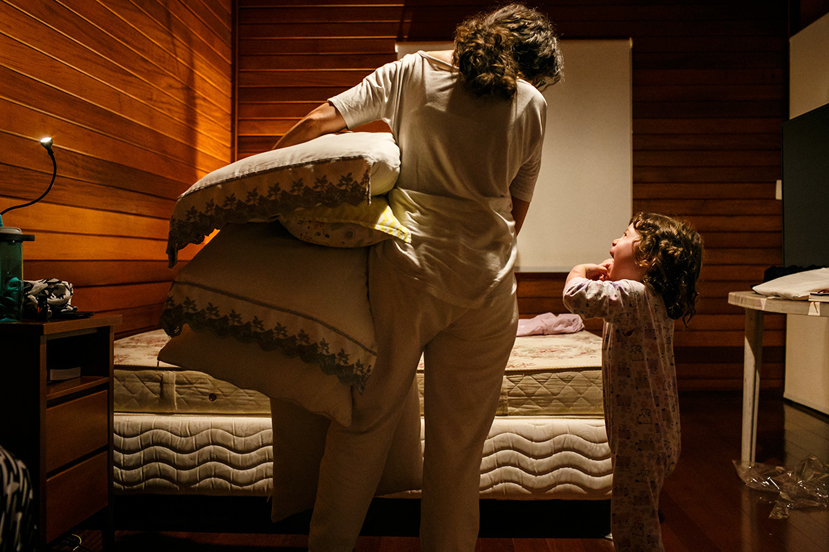 criança ajuda doula a trocar o lençol da cama da mãe que acabou de ter um bebê em casa
