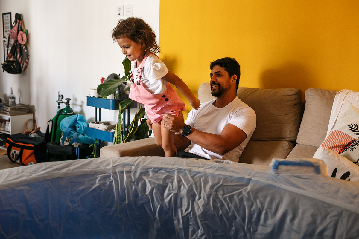 Pai distrai a filha durante o trabalho de parto domiciliar da esposa em foto de Adriana Costa