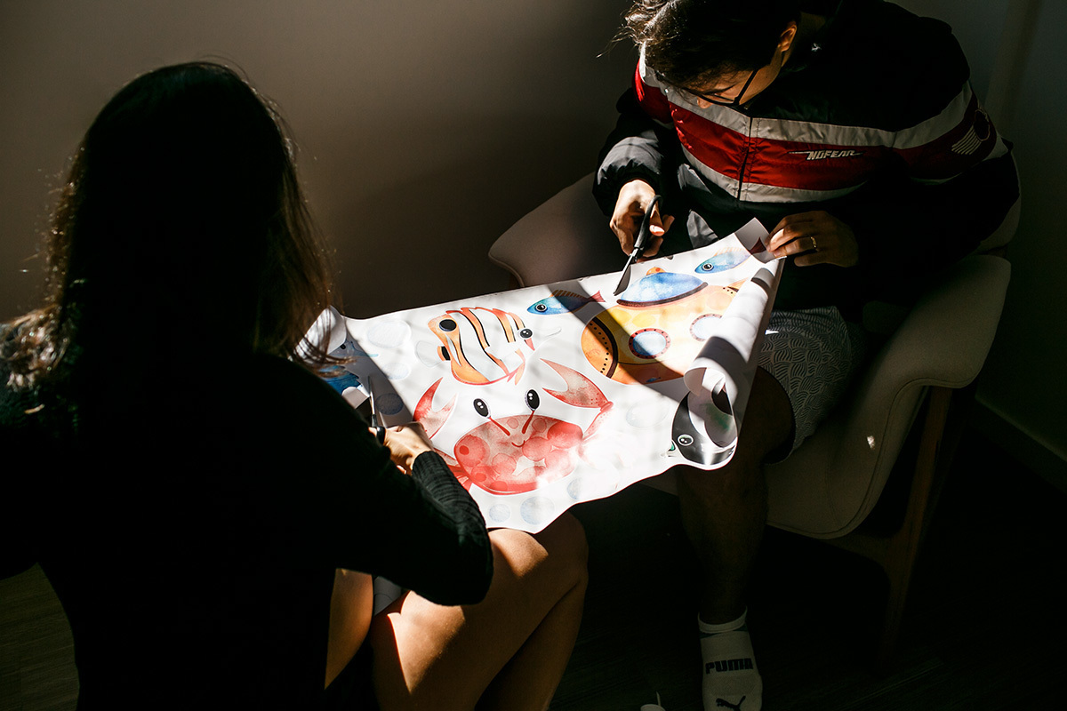Foto de Adriana Costa do casal grávido preparando os adesivos decorativos de parede para o quarto da sua bebê